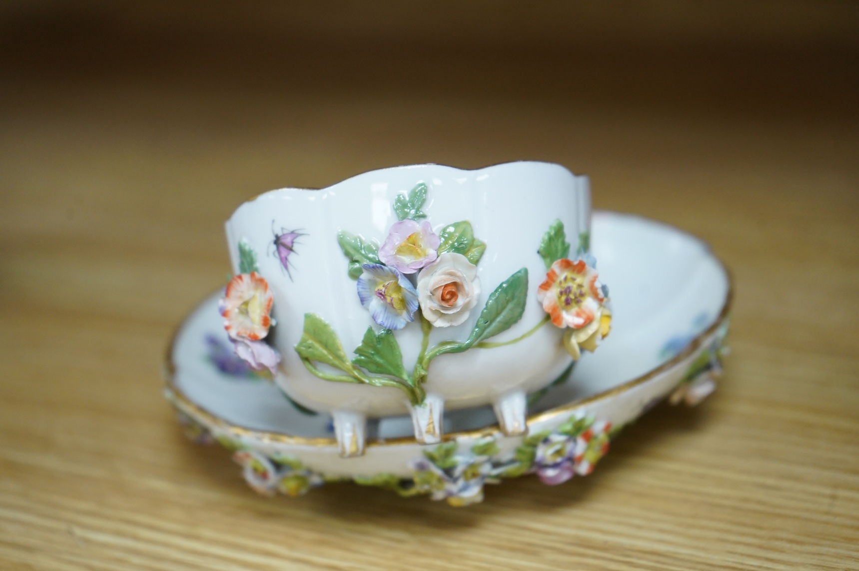 A 19th century Meissen floral encrusted cup and saucer, 14cm diameter